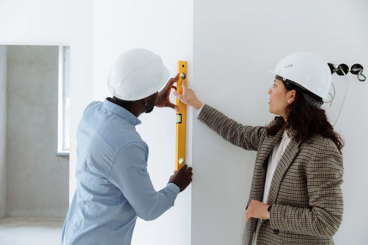 Contractor checking a wall with a level while talking with a homeowner