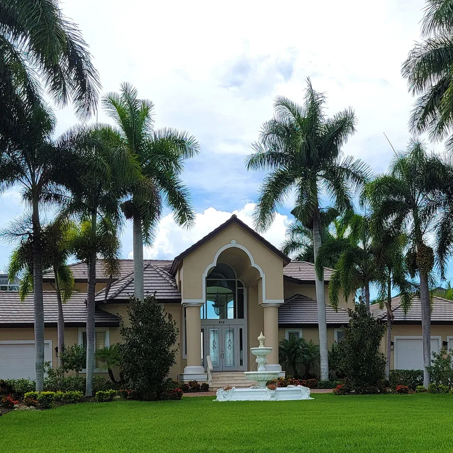 Large Mediterranean-style home with a tile roof and royal palms in Palm Beach County