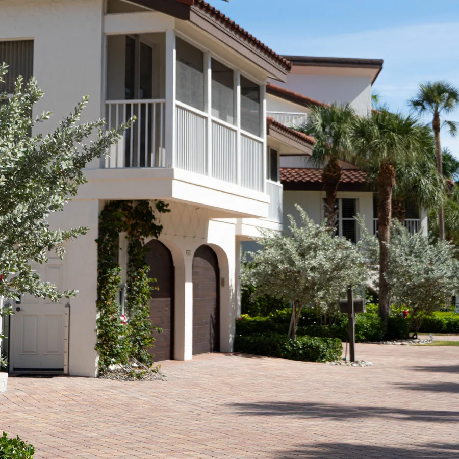 South Florida home with white stucco, arched garage doors and palm trees