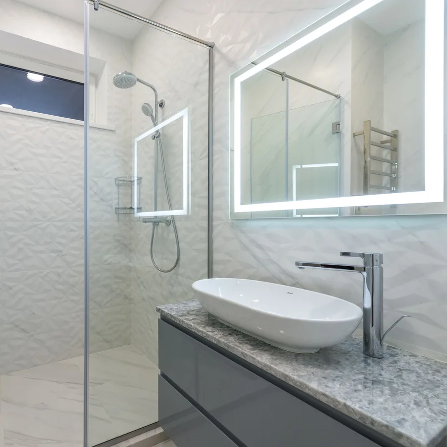 Modern bathroom with a glass shower, vessel sink and lighted mirror