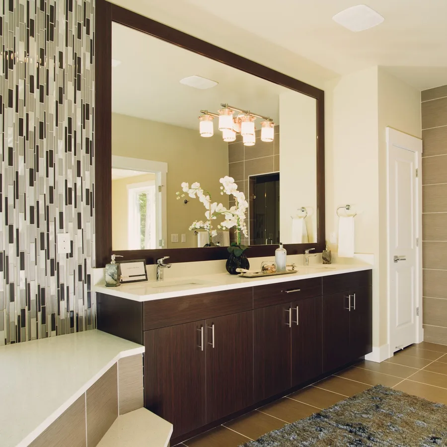 Primary bathroom with a dark wood double vanity, mosaic tile accent wall and tile floor