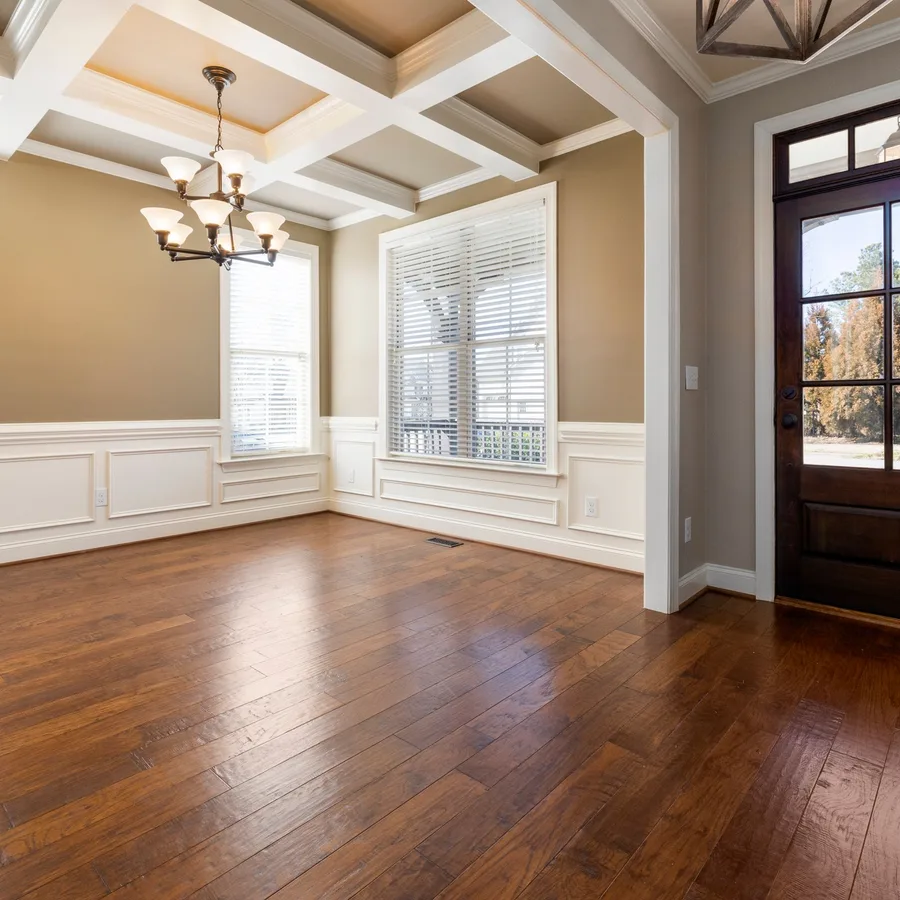 Empty room with new warm wood-look plank flooring, white trim and a large window